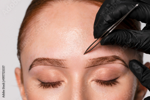 Tableau sur toile Professional brow shaping takes place at a beauty salon with an expert using too