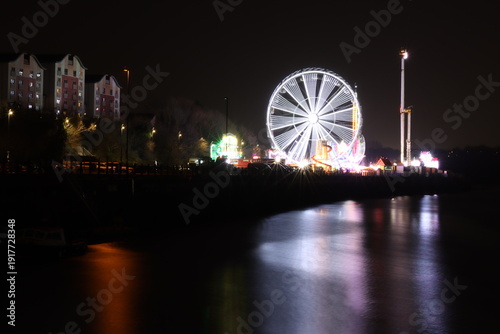 фотографія Lights from a quayside funfair reflected in the water at night