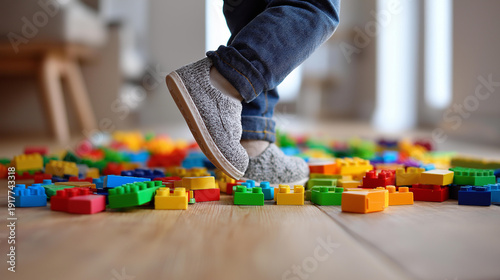 Foot shown stepping on colorful construction toy bricks, scattered floor playtime chaos highlighting, fun messy environment children created, household disorder moment, with copy