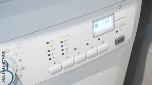 Electronic washing machine panel displays end of program with audible beeping signal. Household appliance finishes cleaning clothes cycle, white laundry equipment with buttons and LED lights.
