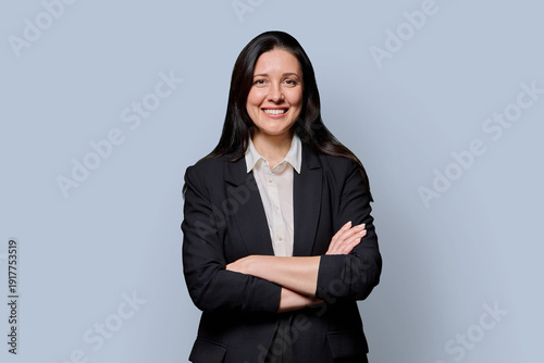 Schilderij op canvas Confident successful middle-aged businesswoman in black jacket on grey studio ba