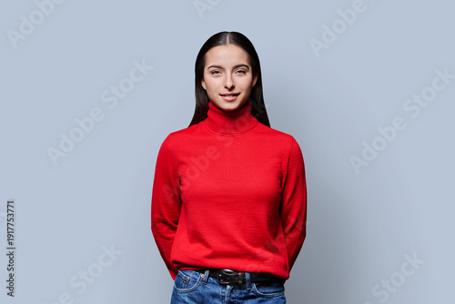 Canvastavla Portrait of beautiful smiling teenage girl in red sweater on gray background