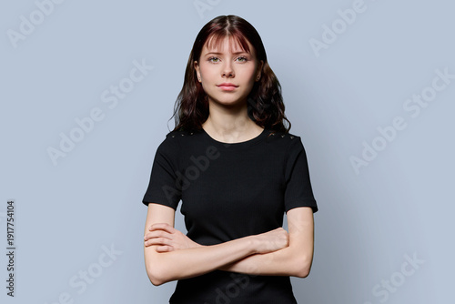 Tableau sur toile Portrait of smiling confident teenage girl with crossed arms on gray background