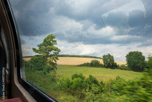 View from train window overlooking agricultural field in motion.
