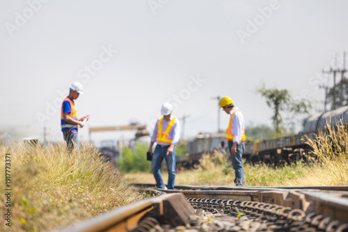 Bild auf Leinwand Close-up of railway tracks with a team of blurred engineers performing a safety