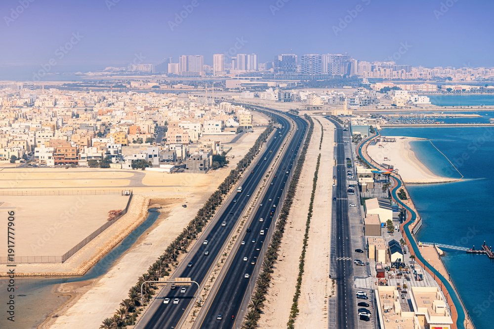 Obraz premium Manama, Bahrain expanding urban development with highway traffic and waterfront promenade by the sea