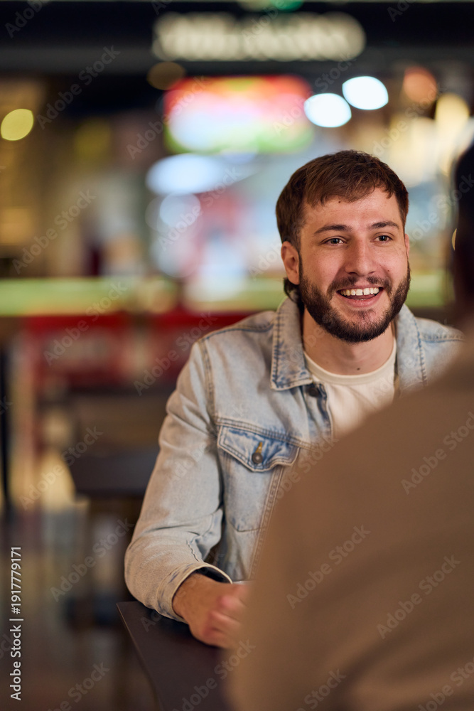 Fototapeta premium Friendly Conversation At A Cafe With A Bearded Man In A Denim Jacket