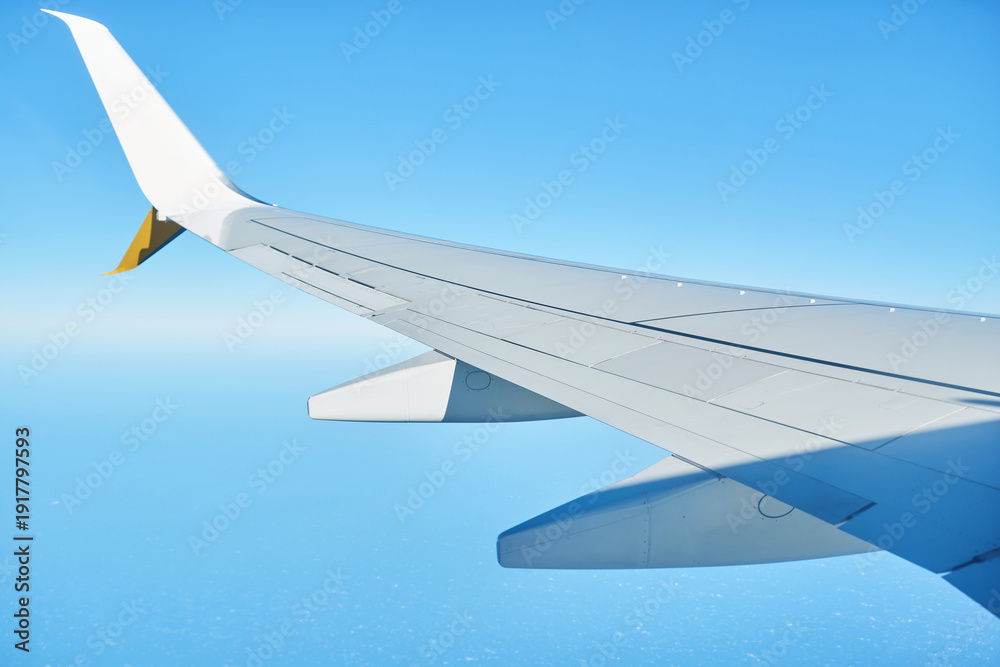 Obraz premium Airplane wing view from window above clouds in clear blue sky