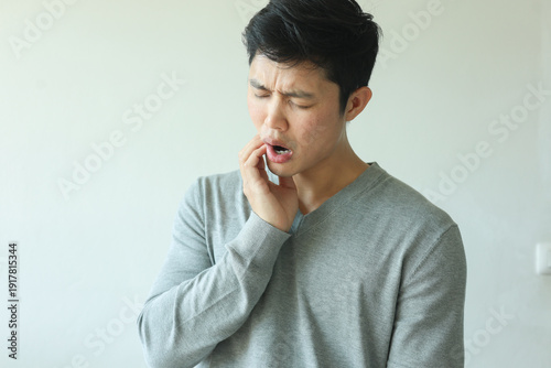 Tableau sur toile close up young asian man frown and use hand to massage on cheek after feeling pa