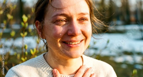 Emotional woman smiling while standing outdoors in spring sunlight  