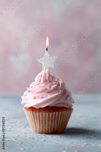 Pink cupcake with star candle on frosting against soft pink background