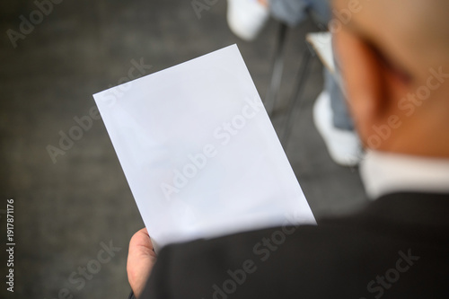 A man in a suit holding a blank sheet of paper