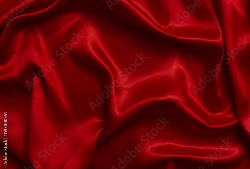 A top-view view of bright red satin fabric, forming beautiful waves.