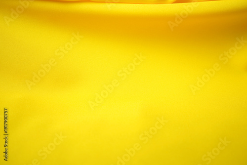 A top-view angle of bright yellow satin fabric with beautiful waves on top.