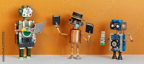 Foto Three robot tech users holding laptop, memory cards and usb stick