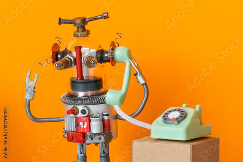 Friendly robot assistant with transparent glass head holding old telephone handset. Helpdesk concept, hotline service flyer