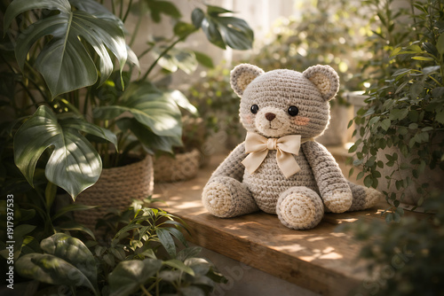 A crocheted teddy bear sits on a wooden shelf surrounded by lush green plants in a serene indoor setting.