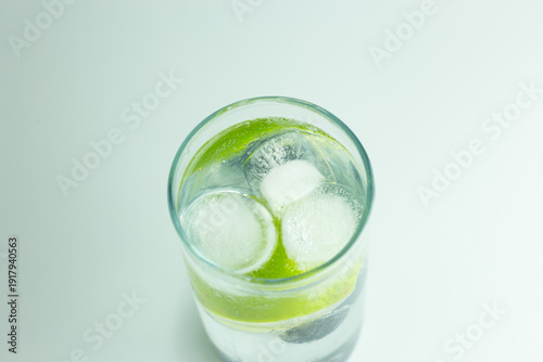 An overhead view of an iced cocktail in a HiBall glass with a slice of lime against a white background