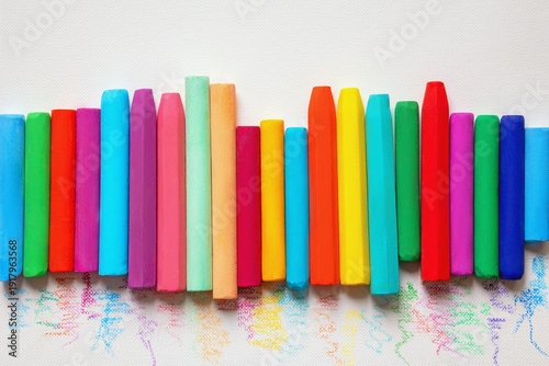Row of colorful oil pastel crayons on white paper for drawing. Copy space