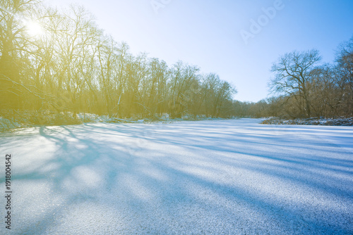 Fotografie frozen river with snowbound forest on coast in light of sparkle sun
