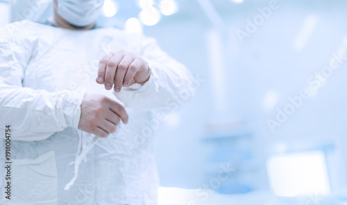 фотографія Person fastening surgical gown sleeves in operating room