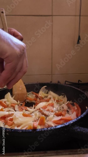 Chef stirring and seasoning sliced vegetables in a cast iron pan