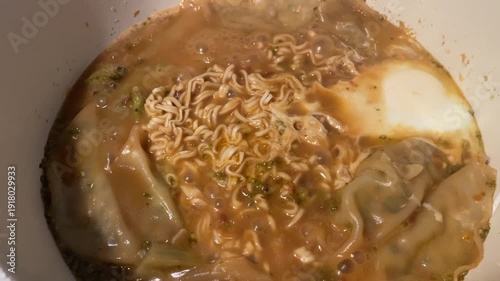 Boiling noodle soup with dumplings closeup