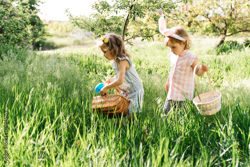 Group Of Children Wearing Bunny Ears Running To Pick Up colorful Egg On Easter Egg Hunt In Garden. Easter tradition