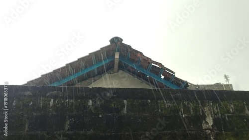 Heavy rain against a backdrop of walls and buildings in a rural setting.
