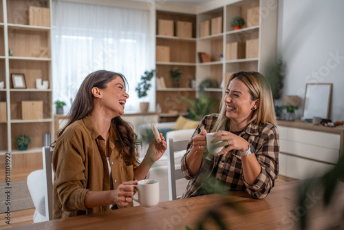 Quadro su tela Happy female friends laughing and connecting over coffee