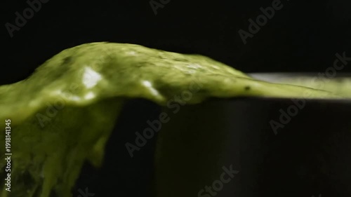 Close up of green liquid spilling in dark setting or Macro of green substance dripping in darkness