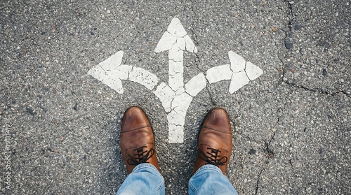 Person standing at crossroads with multiple arrows on asphalt road