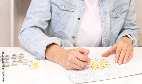 Tableau sur toile Woman practices mindful adult coloring with brush and acrylic paints