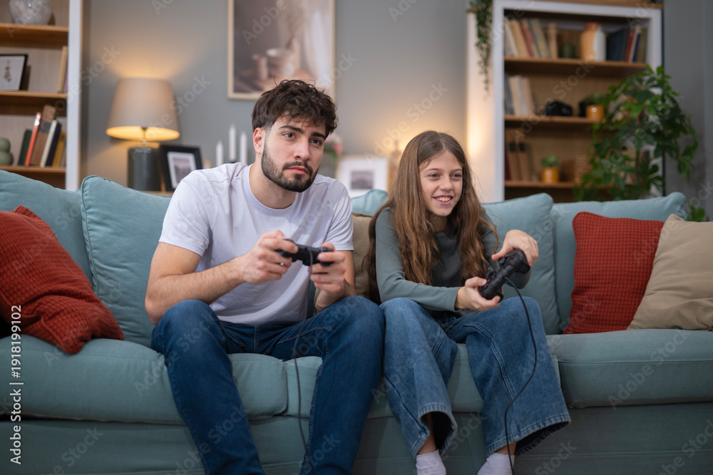 Obraz premium Brother and sister playing video games on sofa at home