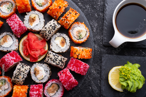 different sushi rolls set with fish beautiful served  at black dishes at black table. top view