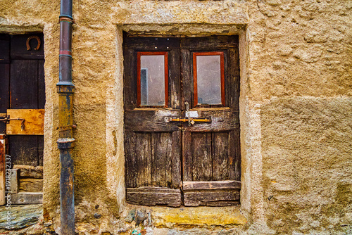 Old ramshackle door on medieval house in Comano, Ticino, Switzerland
