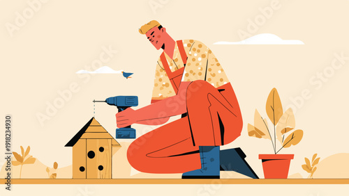 A person in overalls crouches, using a drill to build a wooden birdhouse