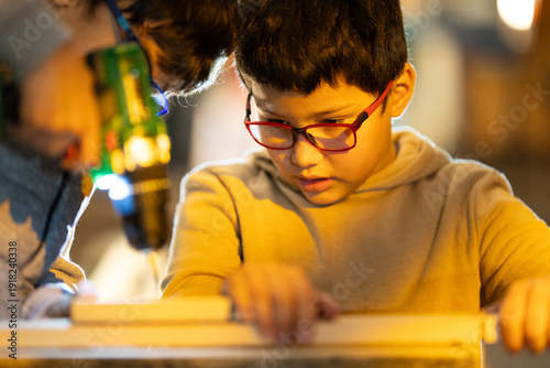 Young boy learning woodworking skills with adult