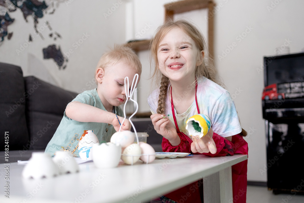 Naklejka premium A boy and a girl paint eggs for Easter.