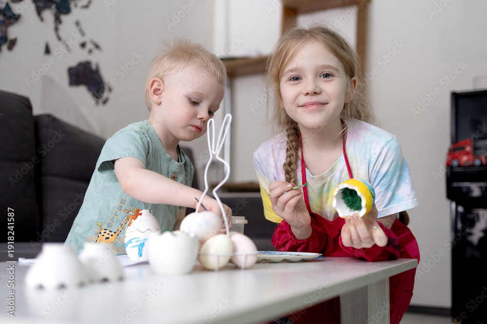 Fototapeta premium A boy and a girl paint eggs for Easter.