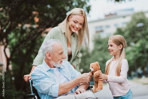 фотографія funny heartwarming scene of grandpa in a wheelchair with granddaughter and mom i