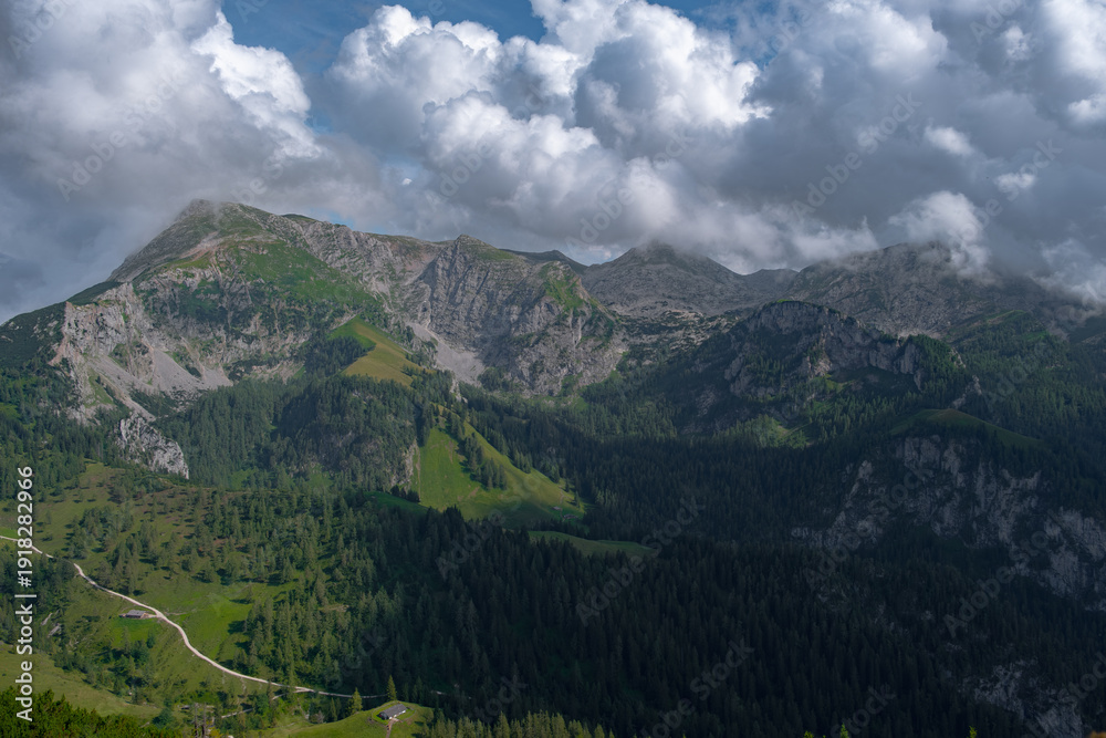 Obraz premium Scenic view of mountains with passing shadows under a bright cloudy sky