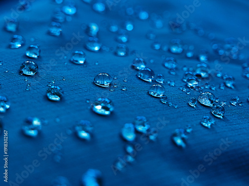 Water drops on waterproof membrane fabric. Detail view of texture of blue waterproof cloth.