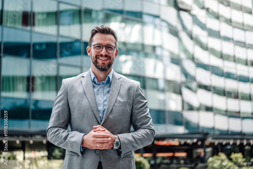 Obraz na plátně Confident businessman smiling standing in front of office building