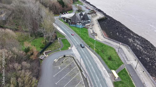 4K aerial flyover of cars driving along Liverpool’s coastal road beside the estuary and promenade.