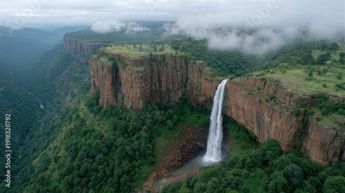 Majestic Waterfall Cascading Down Cliffside Surrounded by Lush Greenery and Misty Mountains in a Serene Natural Landscape