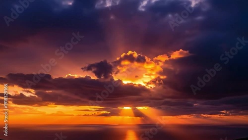 Majestic crepuscular rays pierce through dramatic dark storm clouds during a vibrant tropical ocean sunset creating an awe inspiring natural light display over water.