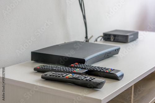 Media players and remote controls on white shelf