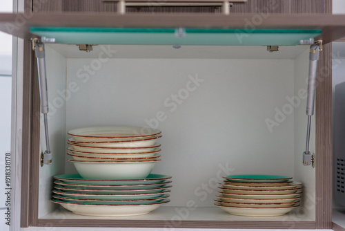Kitchen cabinet with stacked plates and bowls inside