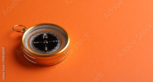 One compass on orange background, closeup. Space for text
